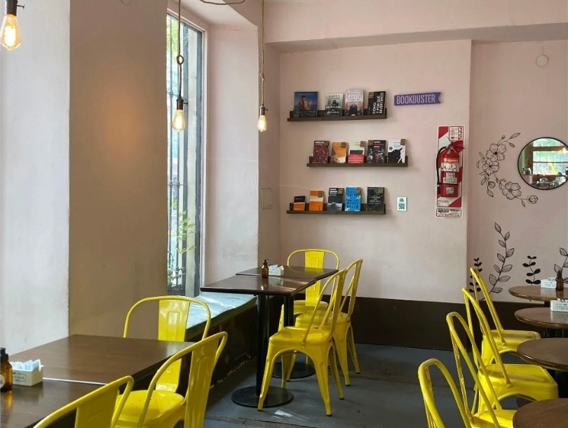 Interior de Matilde con biblioteca, mesas y sillas amarillas